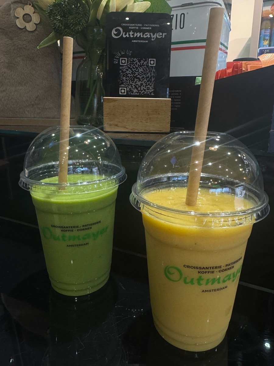 Green and mango smoothies in Outmayer branded cups on the counter
