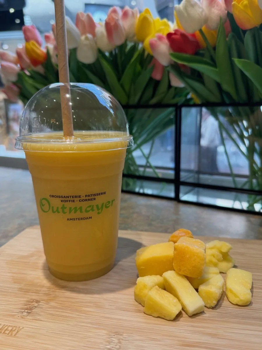 Fresh mango smoothie in Outmayer cup with Amsterdam tulips in the background